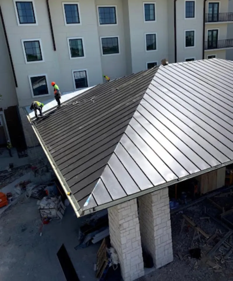 Crew installing standing seam metal roof panels on a commercial project in Trumbull